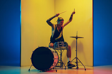 Image showing Young caucasian musician inspired performing on yellow background in neon light