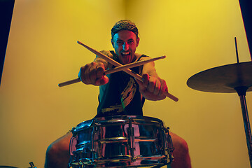 Image showing Young caucasian musician inspired performing on yellow background in neon light