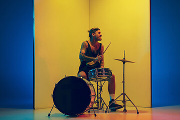 Image showing Young caucasian musician inspired performing on yellow background in neon light