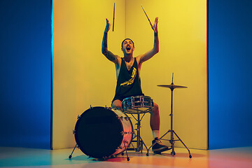 Image showing Young caucasian musician inspired performing on yellow background in neon light