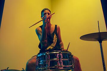 Image showing Young caucasian musician inspired performing on yellow background in neon light