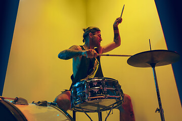 Image showing Young caucasian musician inspired performing on yellow background in neon light