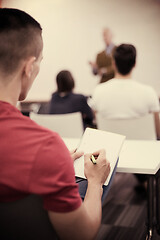 Image showing male student taking notes in classroom