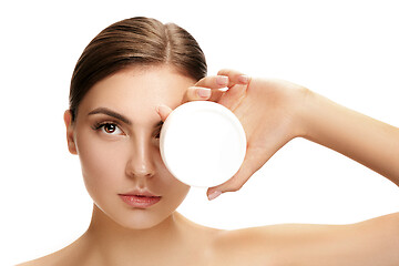 Image showing Cute girl preparing to start her day. She is applying moisturizer cream on face.