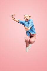 Image showing Young scared caucasian teen girl jumping in the air, isolated on pink studio background.