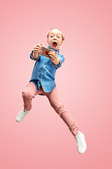 Image showing Young happy caucasian teen girl jumping with phone in the air, isolated on pink studio background.