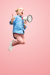 Image showing Beautiful young child teen girl jumping with megaphone isolated over pink background