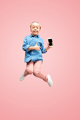Image showing Young happy caucasian teen girl jumping with phone in the air, isolated on pink studio background.