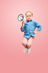 Image showing Beautiful young child teen girl jumping with megaphone isolated over pink background