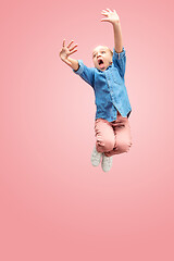 Image showing Young scared caucasian teen girl jumping in the air, isolated on pink studio background.