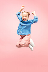 Image showing Young happy caucasian teen girl jumping in the air, isolated on pink studio background.