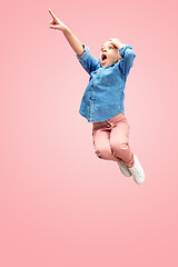 Image showing Young happy caucasian teen girl jumping in the air, isolated on pink studio background.