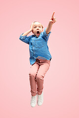 Image showing Young happy caucasian teen girl jumping in the air, isolated on pink studio background.