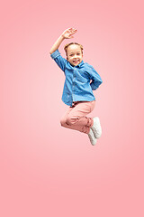 Image showing Young happy caucasian teen girl jumping in the air, isolated on pink studio background.