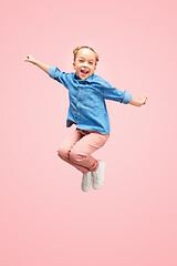 Image showing Young happy caucasian teen girl jumping in the air, isolated on pink studio background.