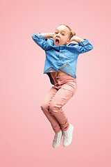 Image showing Young happy caucasian teen girl jumping in the air, isolated on pink studio background.