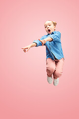 Image showing Young happy caucasian teen girl jumping in the air, isolated on pink studio background.