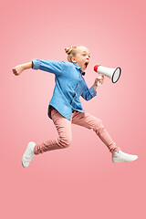 Image showing Beautiful young child teen girl jumping with megaphone isolated over pink background