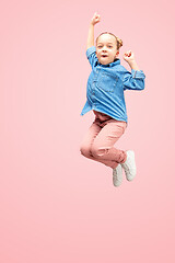 Image showing Young happy caucasian teen girl jumping in the air, isolated on pink studio background.