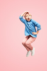 Image showing Young happy caucasian teen girl jumping in the air, isolated on pink studio background.