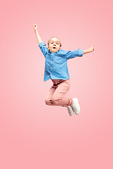 Image showing Young happy caucasian teen girl jumping in the air, isolated on pink studio background.