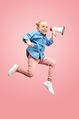 Image showing Beautiful young child teen girl jumping with megaphone isolated over pink background