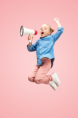 Image showing Beautiful young child teen girl jumping with megaphone isolated over pink background
