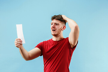 Image showing Young boy with a surprised expression bet slip on blue background