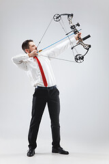 Image showing Businessman aiming at target with bow and arrow, isolated on white background