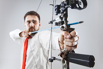 Image showing Businessman aiming at target with bow and arrow, isolated on white background