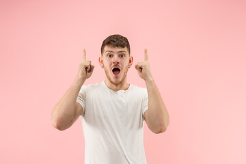 Image showing The young attractive man looking suprised isolated on pink