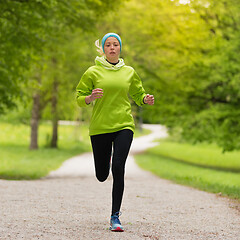 Image showing Sporty young female runner in city park..