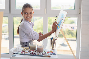 Image showing Girl with a beautiful smile looks into the frame sitting behind 