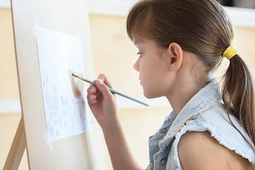 Image showing eight-year-old girl draws a brush pattern on an easel