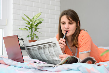 Image showing A girl looks in the newspaper job ads