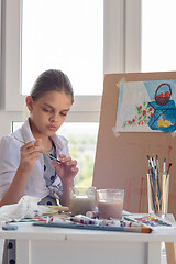 Image showing Girl examines brush for drawing watercolor paints