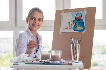 Image showing Smiling girl sits at work in the studio with a brush in her hand