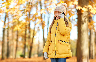 Image showing happy girl calling on smartphone at autumn park