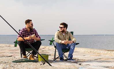 Image showing happy friends fishing and eating sandwiches