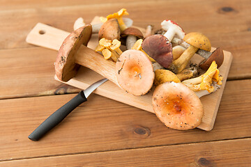 Image showing edible mushrooms on wooden cutting board and knife