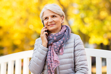 Image showing senior woman calling on smartphone at autumn park