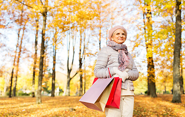 Image showing senior woman with shopping bags at autumn park