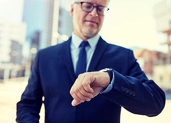 Image showing senior businessman with wristwatch on city street