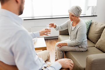 Image showing psychologist giving glass of water to senior woman