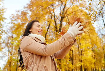 Image showing happy woman having fun with leaves in autumn park