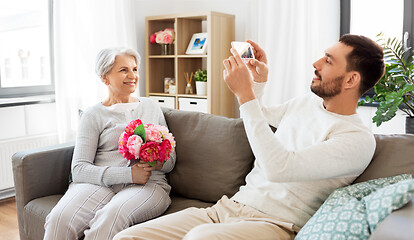 Image showing adult son photographing senior mother at home