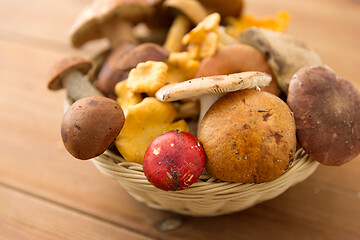 Image showing basket of different edible mushrooms on wood