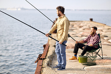 Image showing happy friends with fishing rods on pier