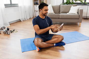 Image showing indian man with smartphone on exercise mat at home