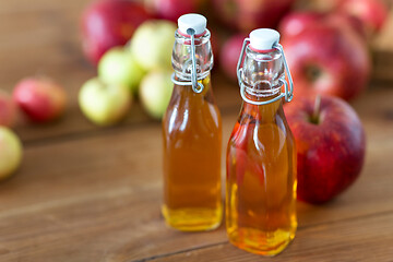 Image showing bottles of apple juice or vinegar on wooden table